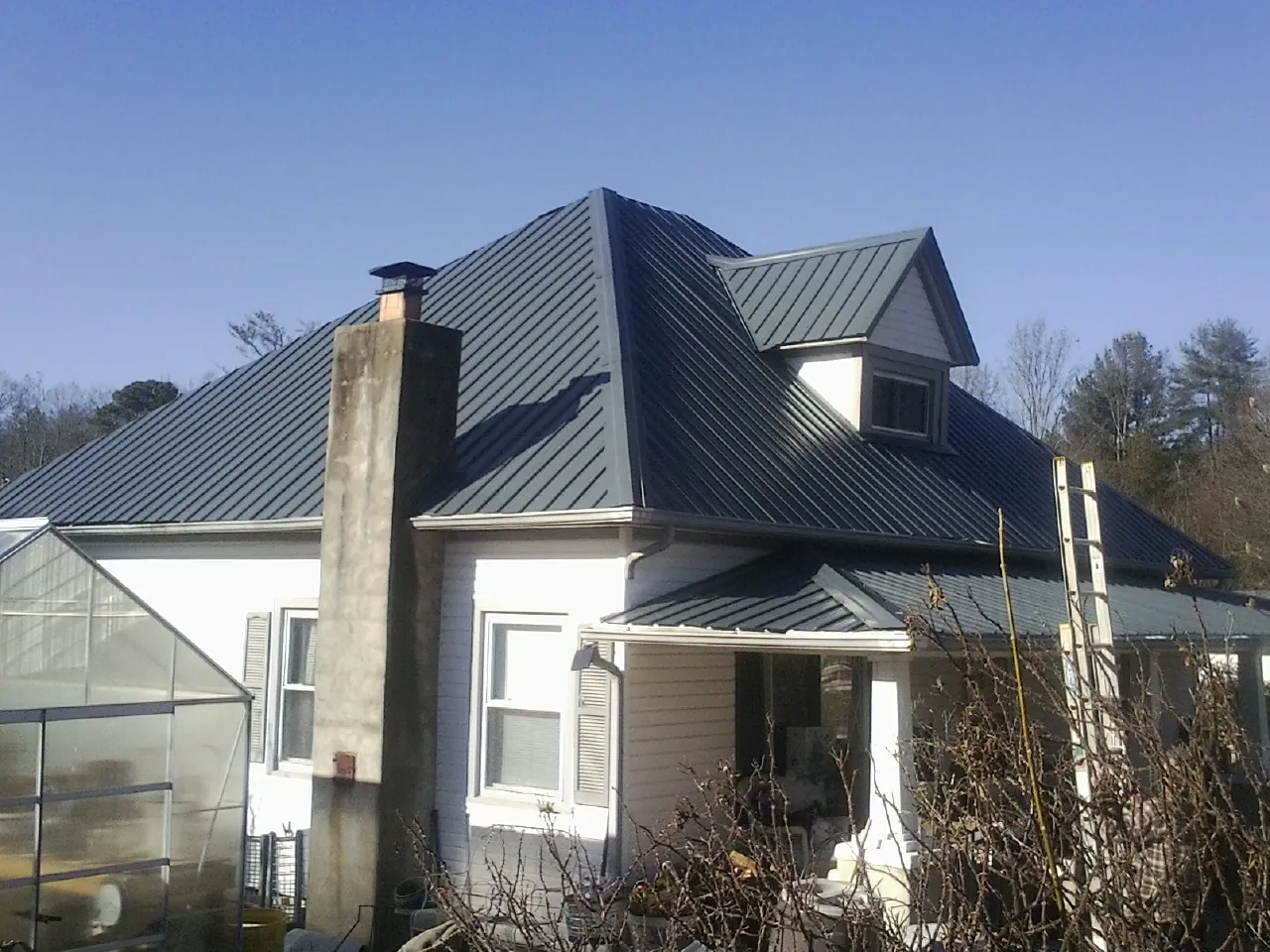 Dark blue standing seam metal roof on a white farmhouse with dormer — Slate & Tile Roof Repair by Roofing Brothers in Bonifay