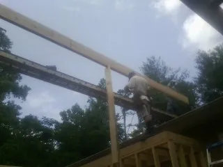 Carpenter setting a ridge beam over a new addition frame — Ice Dam Removal by Roofing Brothers in Bonifay