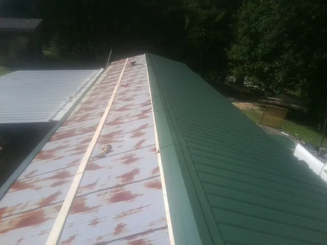 Old rusted panels beside newly installed green metal roofing — Wind Damage Roof Repair by Roofing Brothers in Bonifay