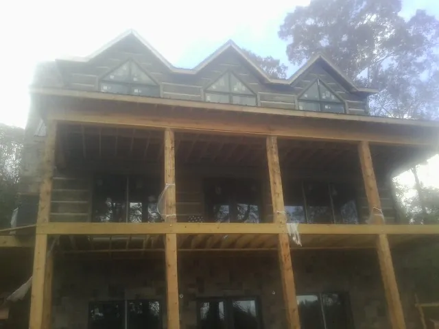 Dormers and porch framing on a large log home under construction — Roof Coating work by our crew in Bonifay