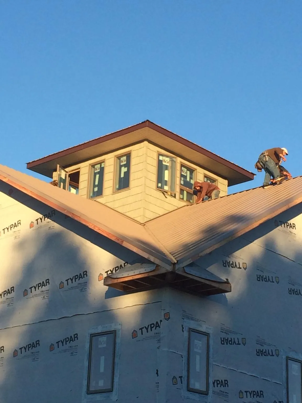 Roofers working around a rooftop cupola on a new metal roof at sunset — Roof Waterproofing in Bonifay by Roofing Brothers
